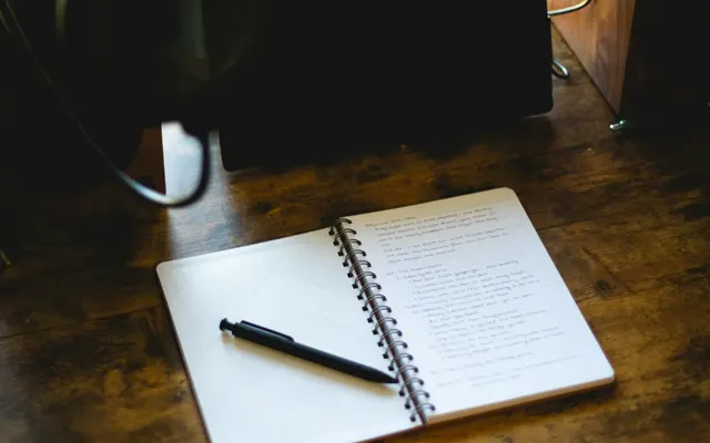 Open notebook and pen on a wooden desk