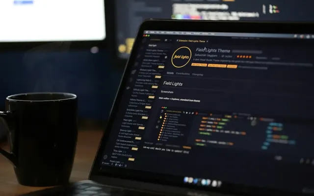 Code editor open on a laptop beside a mug